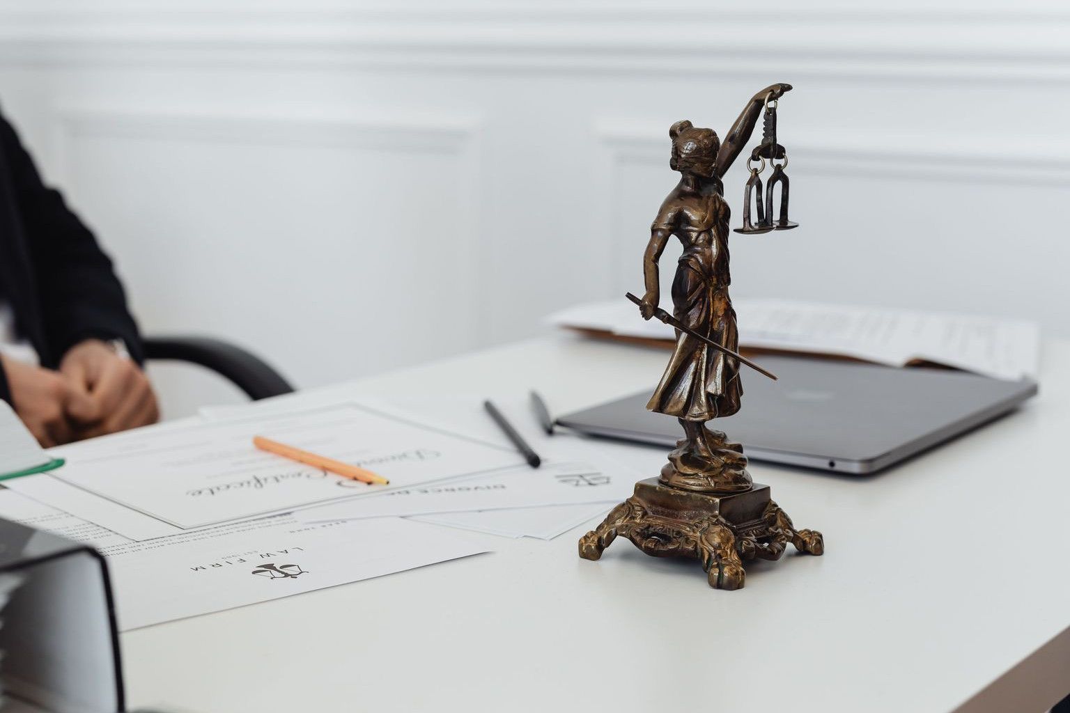 A legal professional's workspace featuring Lady Justice statue, documents, and a laptop.